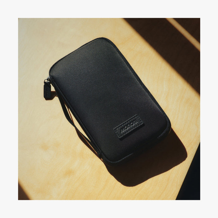 Carbon Black | Angle view of Metro Travel Wallet in Carbon Black on a wooden table