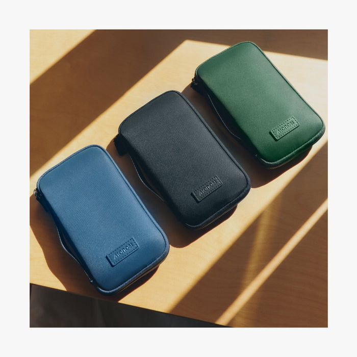 Carbon Black | Metro Travel Wallet in Oxford Blue, Carbon Black and Juniper Green displayed together on a wooden surface