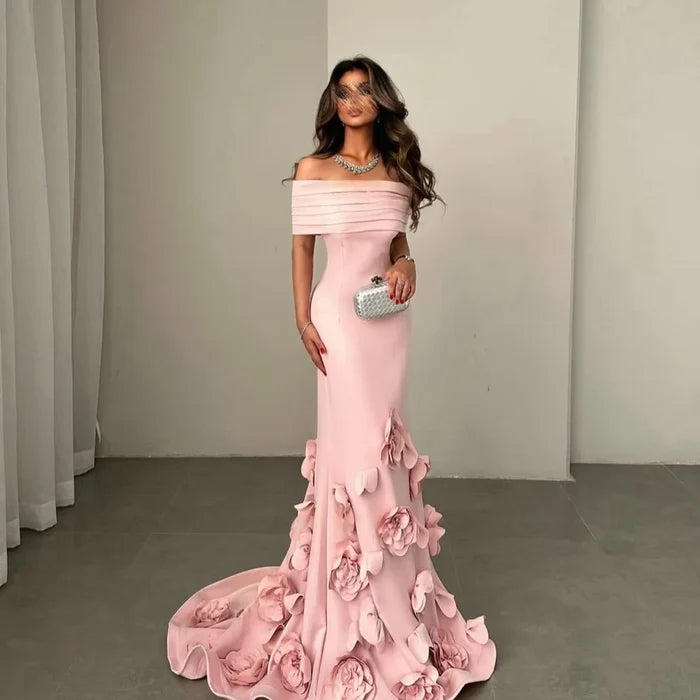 Woman wearing a pink off-shoulder gown with floral details in a neutral setting