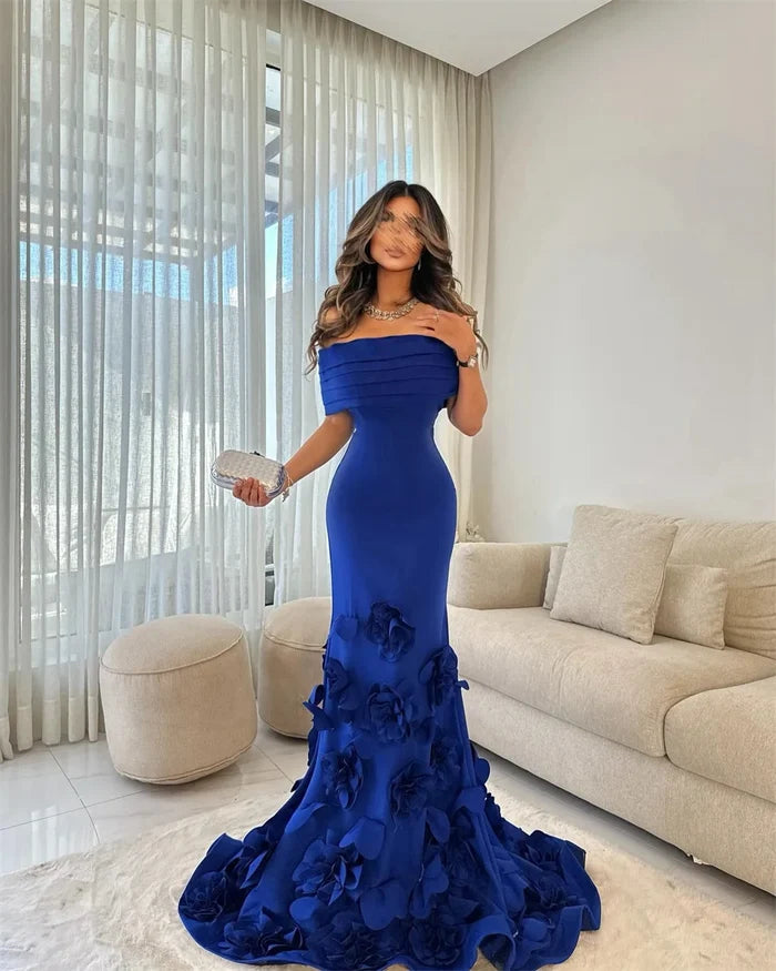 Woman in a blue evening gown standing in a modern living room.