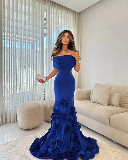 Woman in a blue evening gown standing in a modern living room.