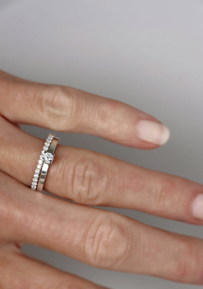 Kvinna som bär set med vigsel och förlovningsringar i silver. Alliansring + solitärring med vita gnistrande diamanter.