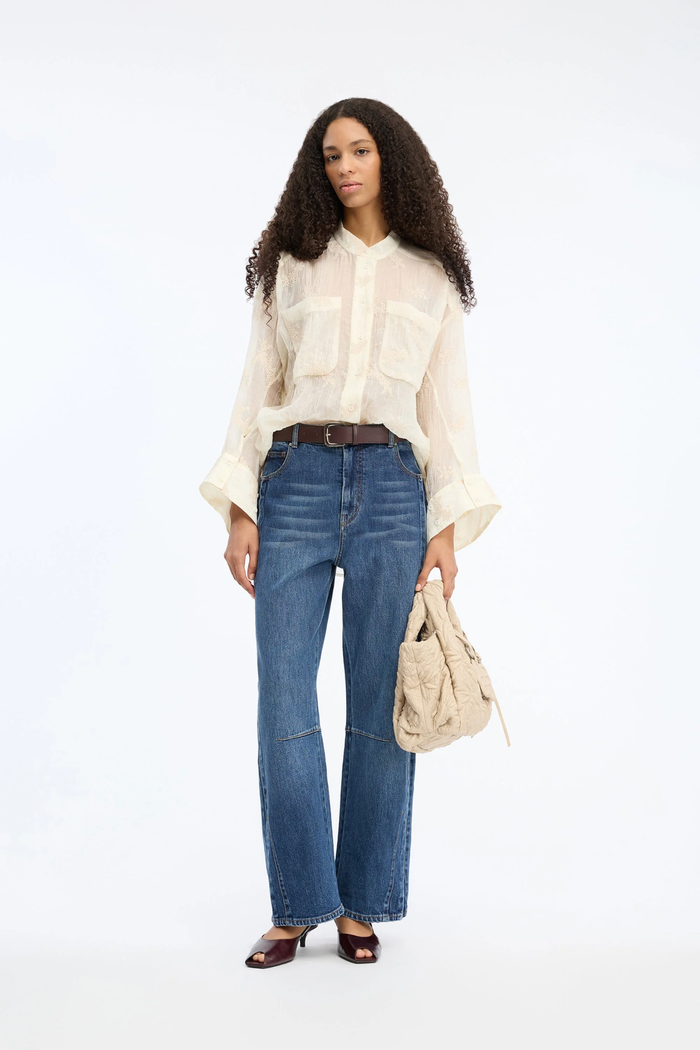 Model wearing the MUNTHE Fortunato Top Crème styled with blue jeans and burgundy heels, shop Munthe at Dotique.