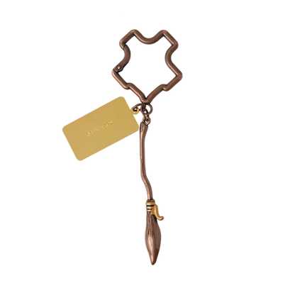 Bronze Nimbus 2000 keychain with a Hogwarts crest-shaped holder and gold tag on a white background