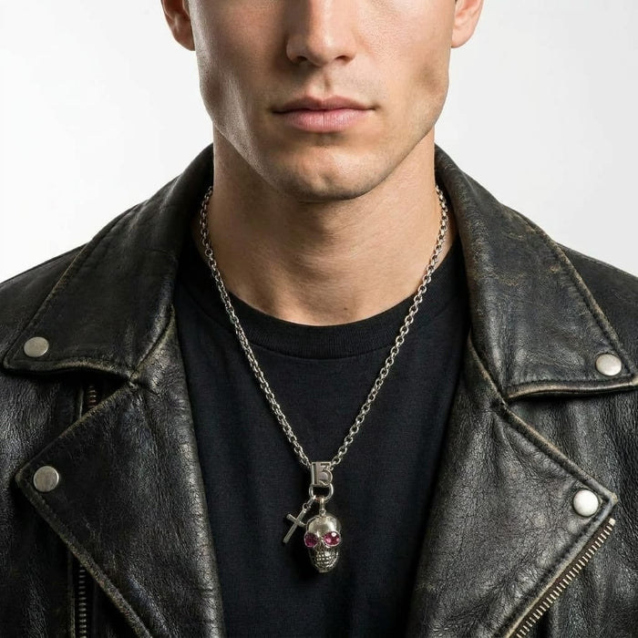 Male model wearing a distressed black leather jacket and a black t-shirt, showcasing a silver biker necklace featuring a number 13, a cross, and a skull charm pendant with red gemstone eyes.