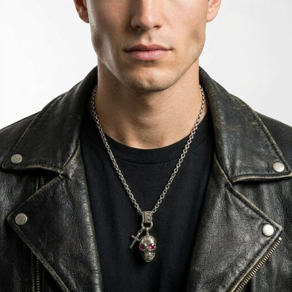 Male model wearing a distressed black leather jacket and a black t-shirt, showcasing a silver biker necklace featuring a number 13, a cross, and a skull charm pendant with red gemstone eyes.