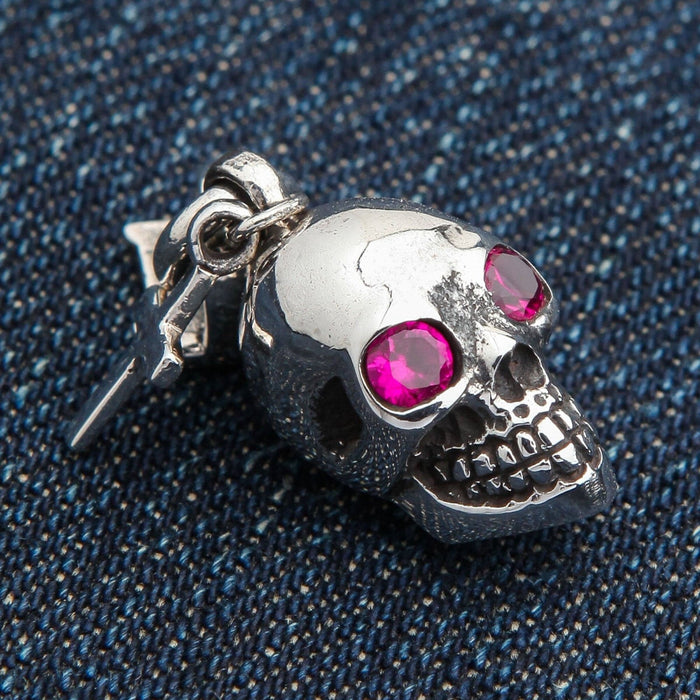 The red eye skull charm pendant with its number 13 bail resting on a blue jeans background.
