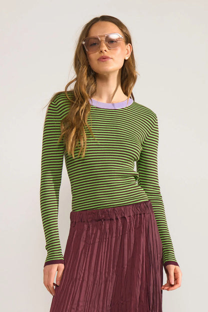 Model wearing Numph 706923 NUFILINA Pullover – Fig with green and black stripes and a lavender neckline, paired with a pleated burgundy skirt by Numph. Shop Numph at Dotique.