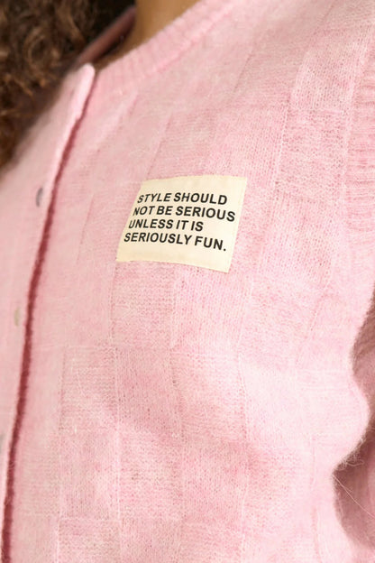 Close-up of a light pink knit vest featuring a motivational patch on the chest, Numph 706928 NURIETTE CHECK VEST – Pink Lady by Numph. Shop Numph at Dotique.