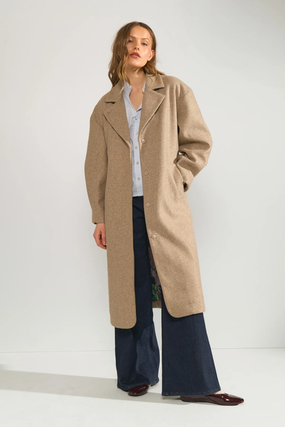 Model wearing Numph 707070 Nulili Blouse Floaty Blue with beige long coat, paired with wide-leg dark jeans and burgundy shoes by Numph. Shop Numph at Dotique.