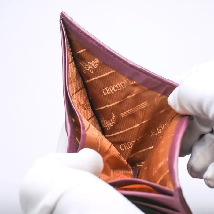 Open cash compartment revealing a patterned brown fabric lining with crocodile logos and plum dyed leather edges.