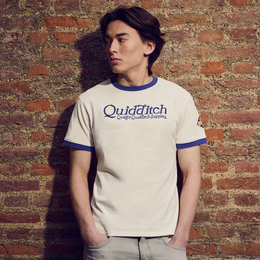 Person wearing a 'Quidditch' t-shirt against a brick wall