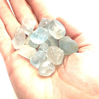 Raw Blue Topaz Gemstone on white grouping center  overview in palm of hand