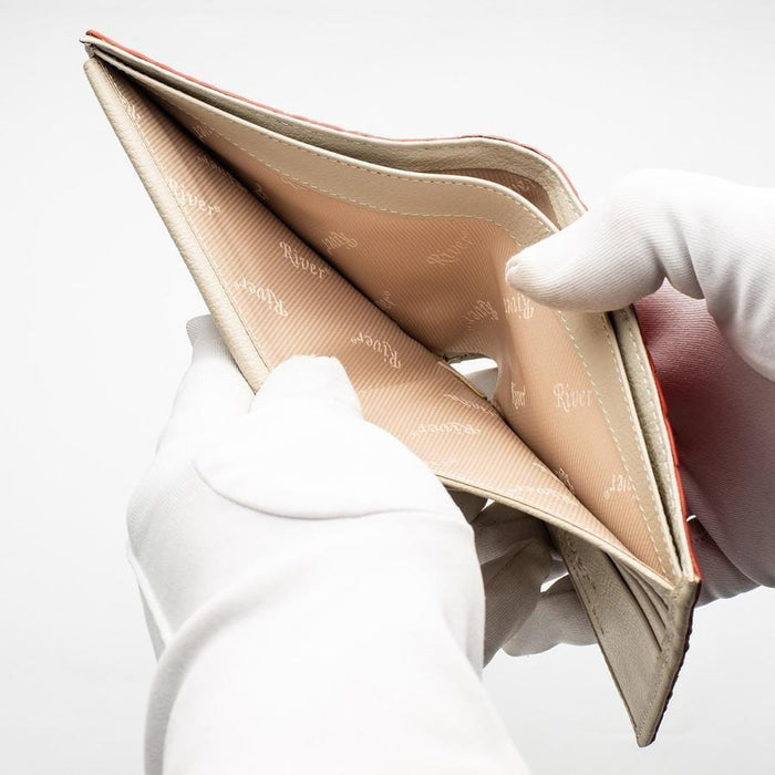 A gloved hand opening the two spacious, fabric-lined bill compartments of the crocodile wallet.