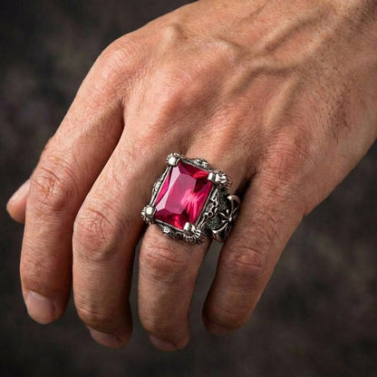 Close-up of a man's hand wearing a large, rectangular red ruby ring set in sterling silver with dragon claw prongs and gothic biker details.