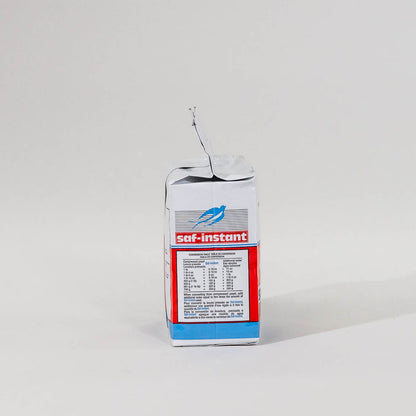 Side view of a single package of Saf Instant yeast on a grey background