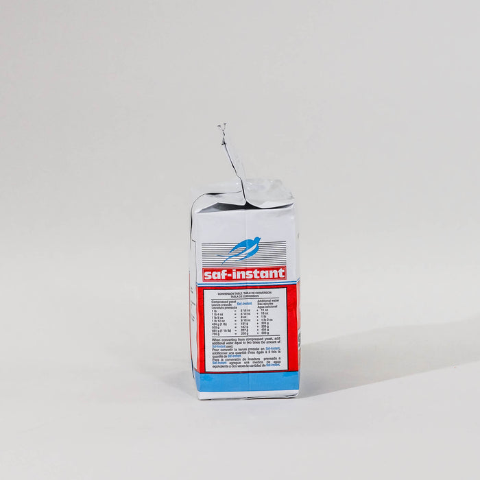 Side view of a single package of Saf Instant yeast on a grey background