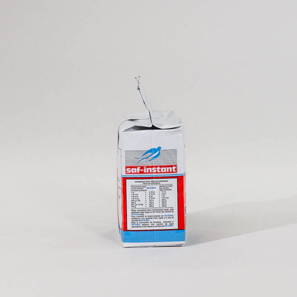 Side view of a single package of Saf Instant yeast on a grey background