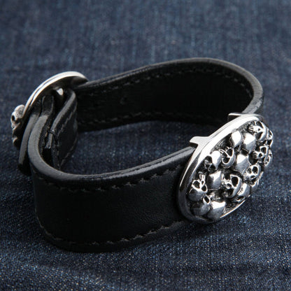 An angled view of the skull stack leather bracelet on a dark denim background.