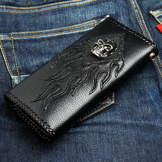 Skull stingray chain wallet lying on denim — flame appliqué cover, braided edge, polished skull on the diamond inlay