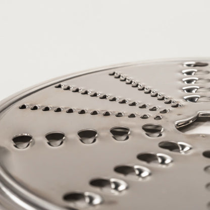 Up close of NutriMill slicer shredder replacement disk - reversible shredding on grey background