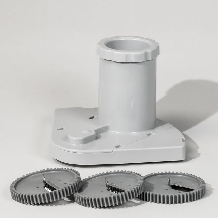 A grey spiralizer attachment with three different blade attachments lying in front of it, designed for creating spiral vegetable garnishes.