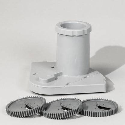 A grey spiralizer attachment with three different blade attachments lying in front of it, designed for creating spiral vegetable garnishes.