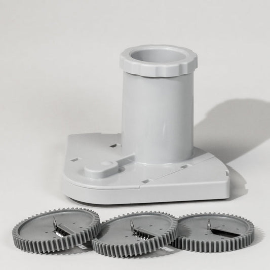 A grey spiralizer attachment with three different blade attachments lying in front of it, designed for creating spiral vegetable garnishes.