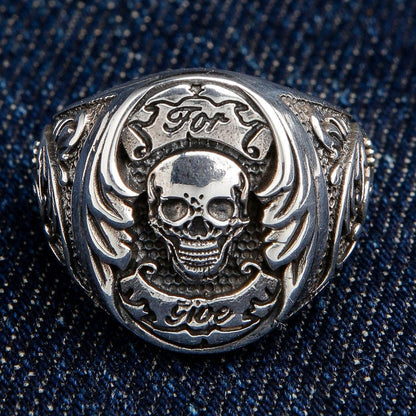 The 'For Life' motto skull ring resting on denim, showcasing its detailed engraving and scrollwork.