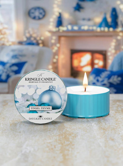 Kringle Candle daylight candle with packaging in a cozy room with a fireplace.