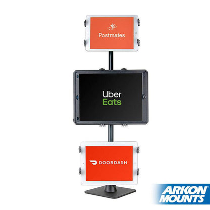 Three tablets on the Triple Slim-Grip® Tablet Holder Stand display the logos of DoorDash, Uber Eats, and Grubhub for restaurant delivery and point-of-sale. The Arkon Mounts logo is in the bottom right corner.