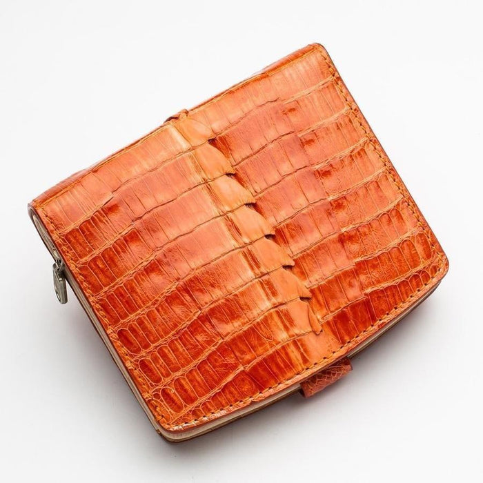 Top-down view of the orange crocodile wallet highlighting the prominent hornback ridge scales and silver zipper hardware along the edge