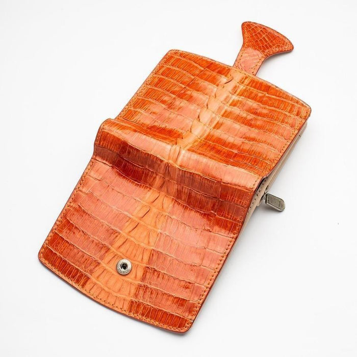 Open flap interior showing snap button fastener and glossy two-tone orange crocodile scale texture with silver clasp hardware