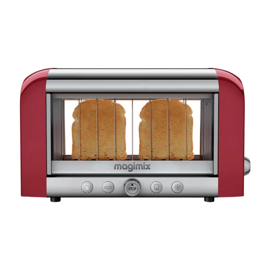 A red Magimix toaster with transparent glass side windows showing toasting bread, featuring stainless steel and borosilicate glass construction with control buttons on the front.