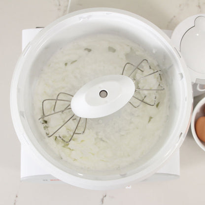 Bosch white universal plus mixer mixing white frosting on a white kitchen counter