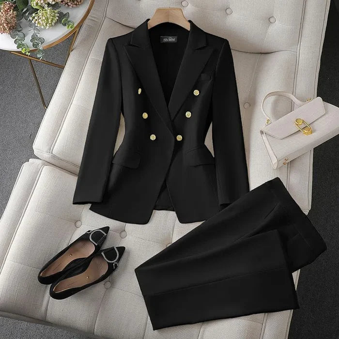 Black suit with gold buttons on a white chair, accompanied by black shoes and a white handbag.