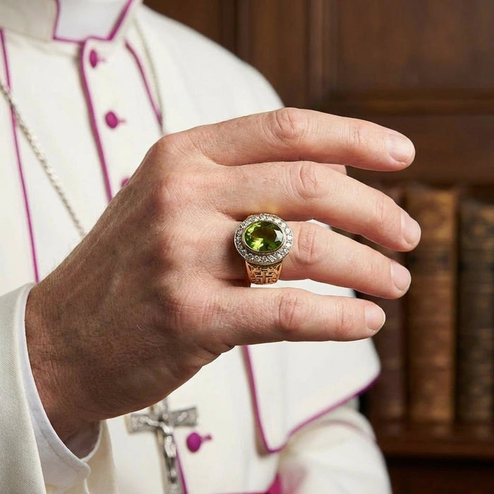 Peridot bishop ring worn on hand over white and magenta clergy vestment with crucifix necklace visible