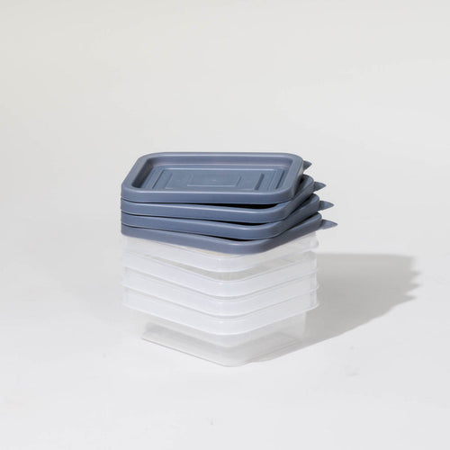 Stack of NutriMill clear plastic yogurt containers with blue-grey lids on a white background